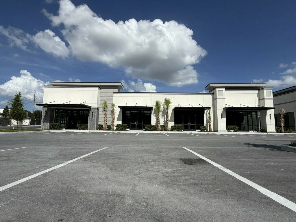 Real photograph of Building 5, showing four storefront entrances and parking